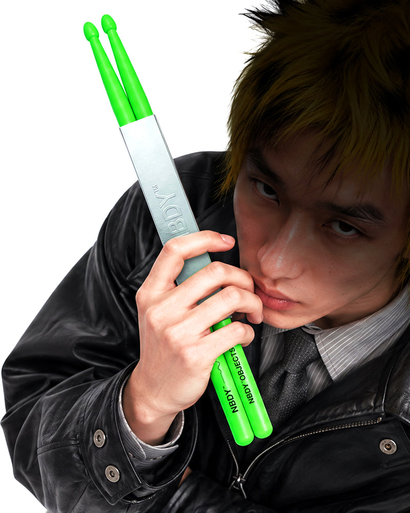 Model holding a pair of NBDY drumsticks to his face