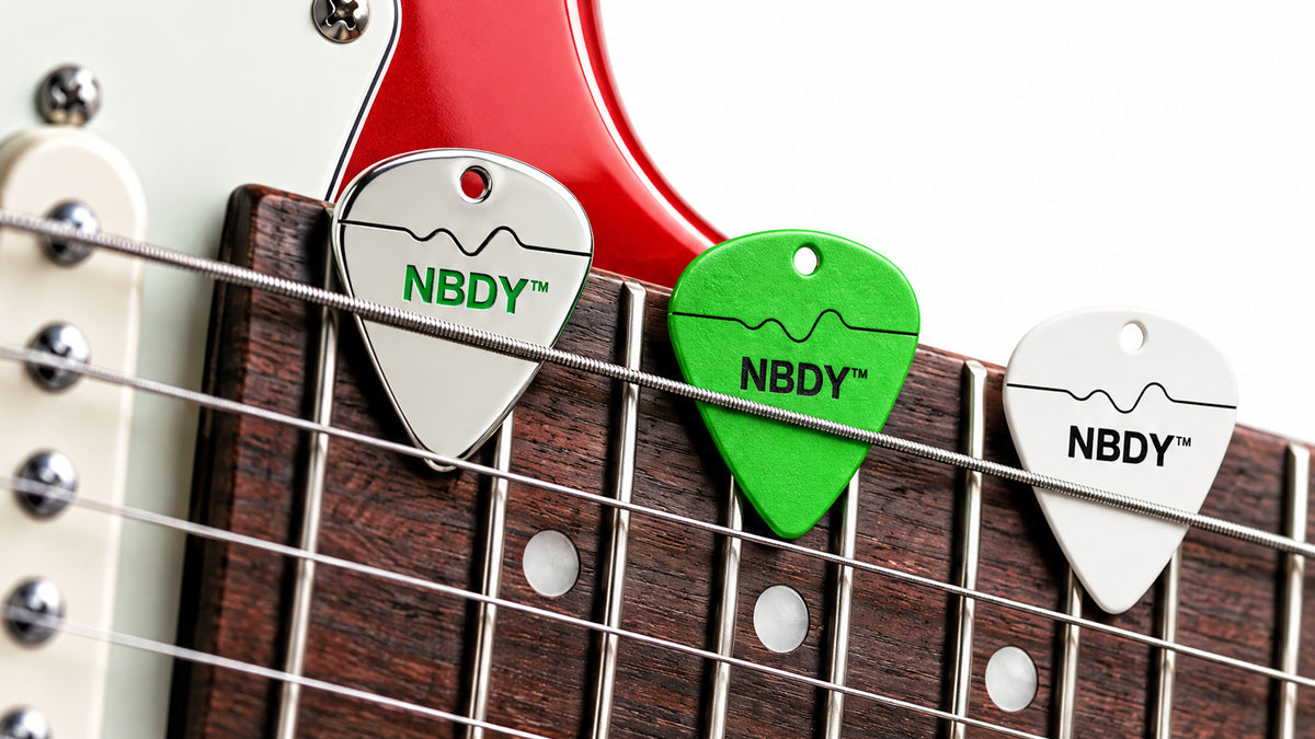 NBDY guitar picks tucked into the strings of a red electric guitar