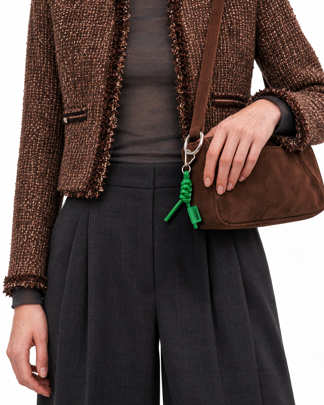 Model in a tweed jacket with the NBDY keychain hanging from her bag