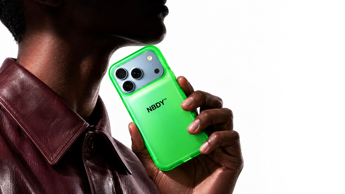 Model in profile holding an iPhone in the green NBDY case