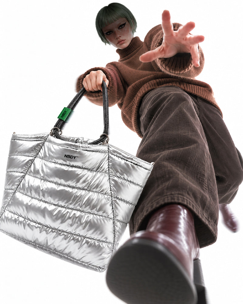 Model lunging forward with the silver NBDY tote bag