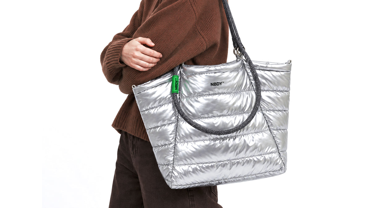 Model carrying the silver quilted NBDY tote bag on her shoulder
