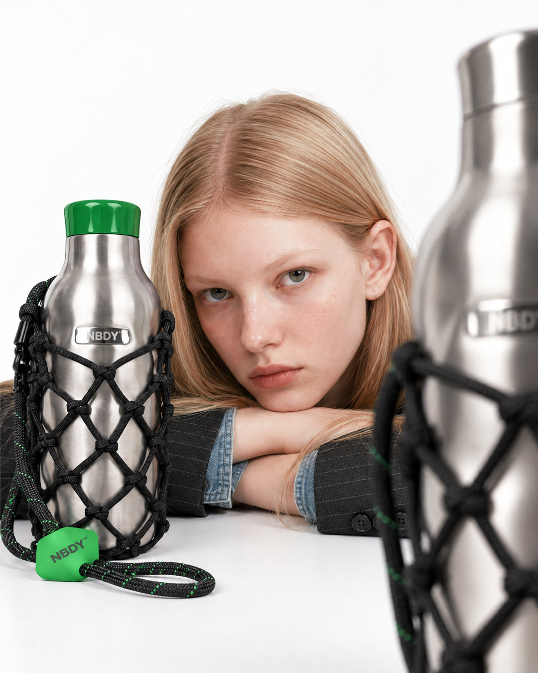 Model resting her head behind the NBDY tumbler in its net holder
